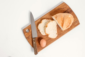 Fototapeta na wymiar White bread lies on a kitchen board with a knife view from above on a white background