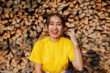 Young funny girl with bright make-up,  wear on yellow shirt against wooden background.