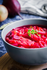 Roasted garlic beetroot soup on dark blue background. Selective focus, copy space, close up.