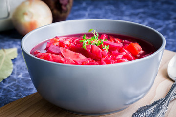 Borscht, vegetarian beetroot soup and ingredients on dark blue background. Selective focus, copy space, close up.
