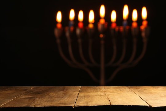 Empty wooden table in front of jewish holiday Hanukkah background with menorah (traditional candelabra).