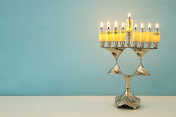 image of jewish holiday Hanukkah background with menorah (traditional candelabra) and burning candles.