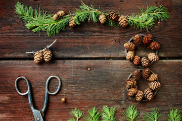 Christmas background on old wooden boards with decorative element in the shape of a figure eight, antique scissors and cones of larch