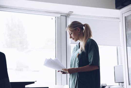 Nurse Reading Papers In Doctor's Office