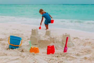 little girl building sand castle on beach