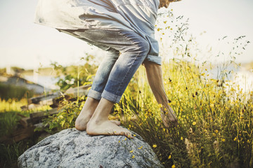 Low section of young man standing on rock by flowers