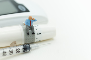 Miniature person sitting on a glucose meter health care concept.