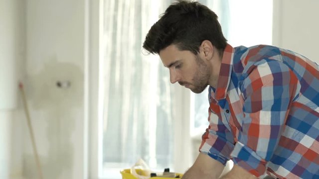 Young man working on laptop standing by table at new home
