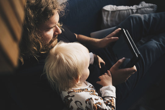 Father and baby daughter looking at digital tablet