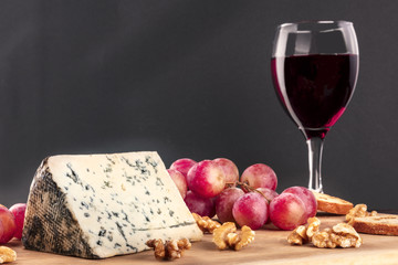 Blue cheese, grapes, and wine on black with copyspace
