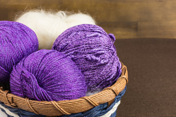 Fototapeta na wymiar balls of purple and white knitting wool in wooden basket