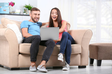 Young couple with laptop on sofa at home