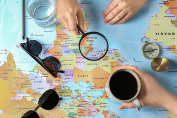 Female tourists explore world map with magnifying glass at table