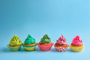 Tasty cupcakes on color background