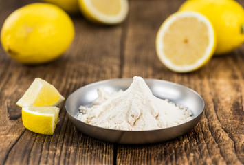 Old wooden table with fresh Lemon powder (close-up shot; selective focus)