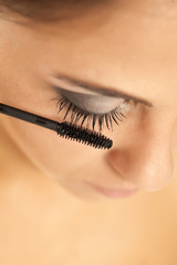 young beautiful woman applied mascara on her eyelashes