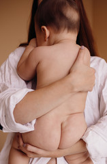 Mother holds tender naked child in her arms