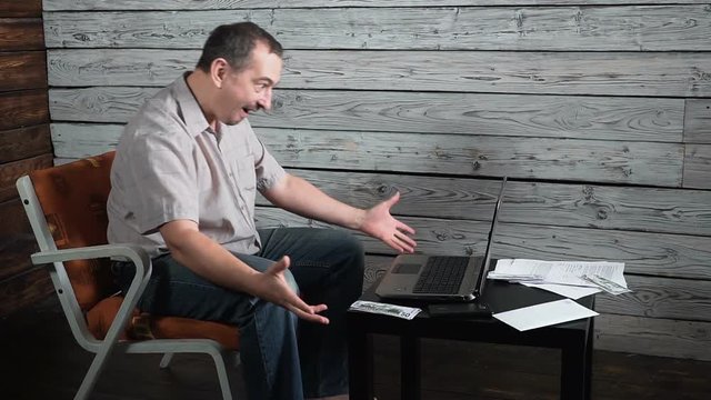 fifty year old crazy man checks online account and celebrates winning on his laptop computer