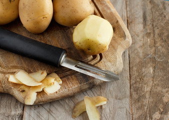 Raw potatoes with a vegetable peeler