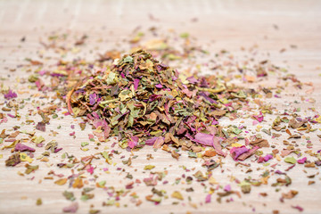 leaves amaranth tea, scattered on the wooden table. Mound of tea leaves of amaranth tea. Dried crushed leaves of amaranth.