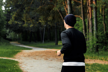 Morning jog in the park, a man in a black sports suit running around the park copy space