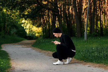 A man is doing exercises preparing for morning workout in a green park on a summer morning