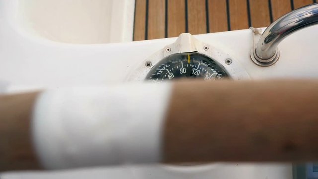 Looking at sailing boat compass from skippers prespective. Steering wheel turning in slow motion hd.