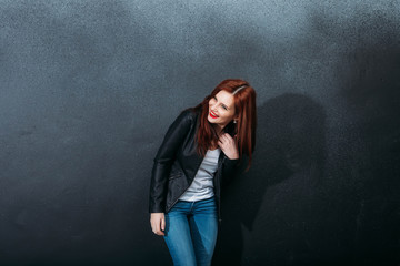 Portrait of beautiful rouge young woman standing against wall with arms at jacket