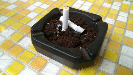 Ashtray closeup full of smoked cigarettes in the sand