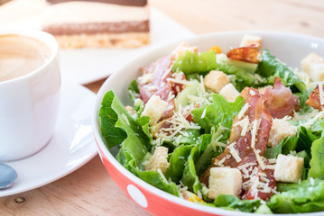 Caesar Salad with Cheese and Bacon on a wooden table in cafe.