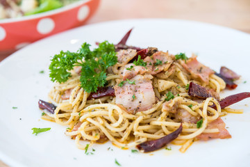 Spicy spaghetti with bacon and cheese on a wooden table in a restaurant.