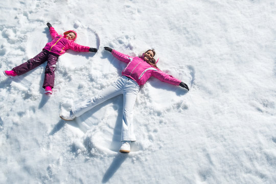 Daughter and mother laying on snow