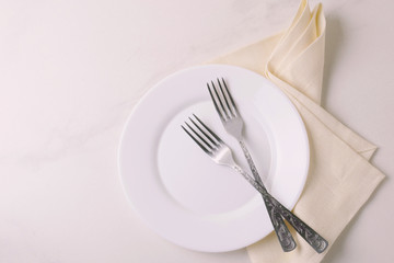 Food background. White empty plate, cutlery, napkin. Top view, copyspace.