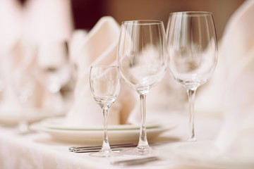 Close up of empty wine glasses set in restaurant. Banquet table set. White tablecloth. Catering services.