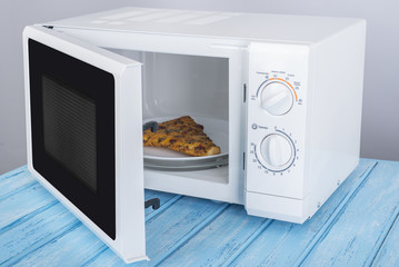 A new white microwave oven, on a blue wooden surface for heating food