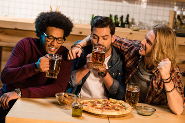 friends with pizza and beer in bar