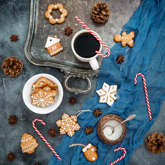 Obraz na płótnie Canvas Christmas or New year composition with gingerbread, candy cane and coffee cup on dark background. Food concept. Flat lay. Top view