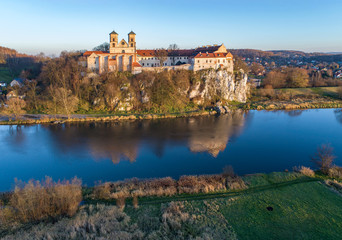 Fototapeta na wymiar Tyniec near Krakow, Poland. Benedictine abbey on the rocky cliff and its reflection in Vistula River. Aerial view in fall in sunset light