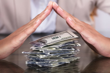 Businesswoman Hand Protecting Stack Of Hundred Dollar Bills