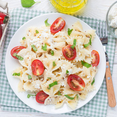 Fototapeta na wymiar Pasta salad with tie pasta, feta cheese, cherry tomatoes, mustard and basil, top view, square format