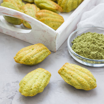 Matcha green tea madeleines on table and in wooden tray, square