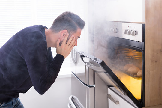Shocked Man Looking At Burnt Cookies In Oven