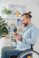 man on wheelchair writing in notebook