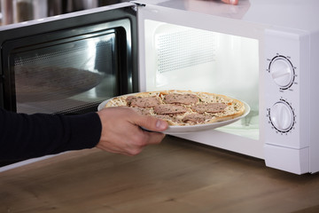 Human Hand Baking Pizza In Microwave Oven
