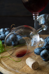 Two wineglasses with red wine and grapes decorated vine leaves on dark wooden desk