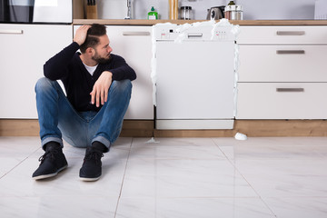 Upset Man Sitting Next To Dishwasher