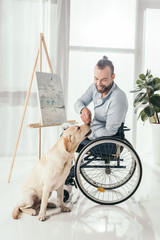 disabled man painting and petting dog