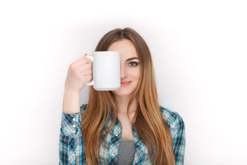 Portrait of a young adorable blonde woman in blue plaid shirt enjoying her warm cozy drink in big blank white mug.