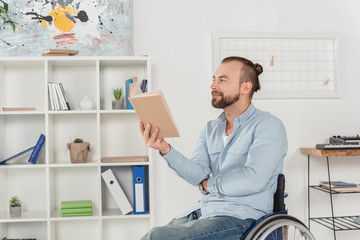 man on wheelchair reading book