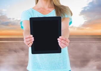 Woman holding tablet with evening sky background